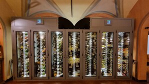 A wine cellar with multiple glass-fronted cabinets, each containing rows of wine bottles. - Ristorante Albergo Corona (Novi Ligure)