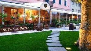 A restaurant with outdoor seating, a sign reading "TENUTA SAN PIETRO," and a pathway leading to the entrance. - Ristorante Albergo Corona (Novi Ligure)
