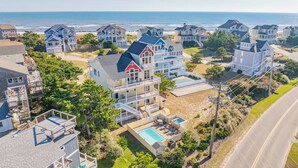 A coastal residential area with houses featuring balconies and a swimming pool. - Semi-Oceanfront Hatteras Home with Private Pool, Hot Tub, Game Room and Wet Bar (Hatteras)