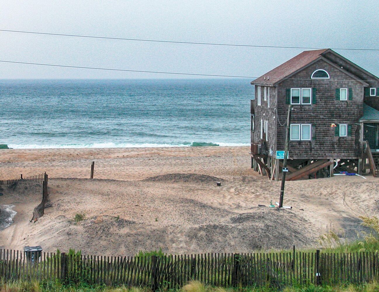 A wooden house on stilts by the beach with a view of the ocean.