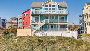 Un edificio frente a la playa con varios pisos, balcones y una escalera.