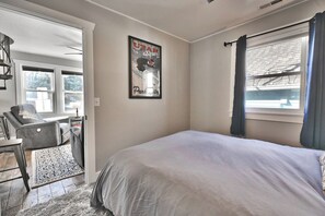A bedroom with a bed, a chair, a rug, a poster on the wall, and a window with curtains. - Bubba's Blue Bungalow WALK to Lifts and Main St (Park City)