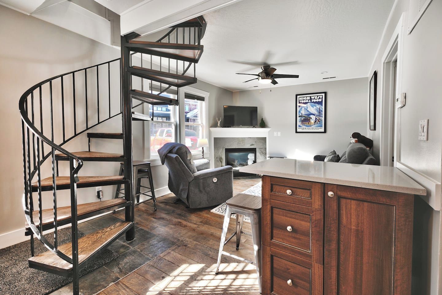 Una cocina moderna con una isla integrada, una escalera en espiral y una chimenea.