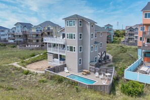 A multi-story residential building with a pool, outdoor seating, and a view of neighboring houses.