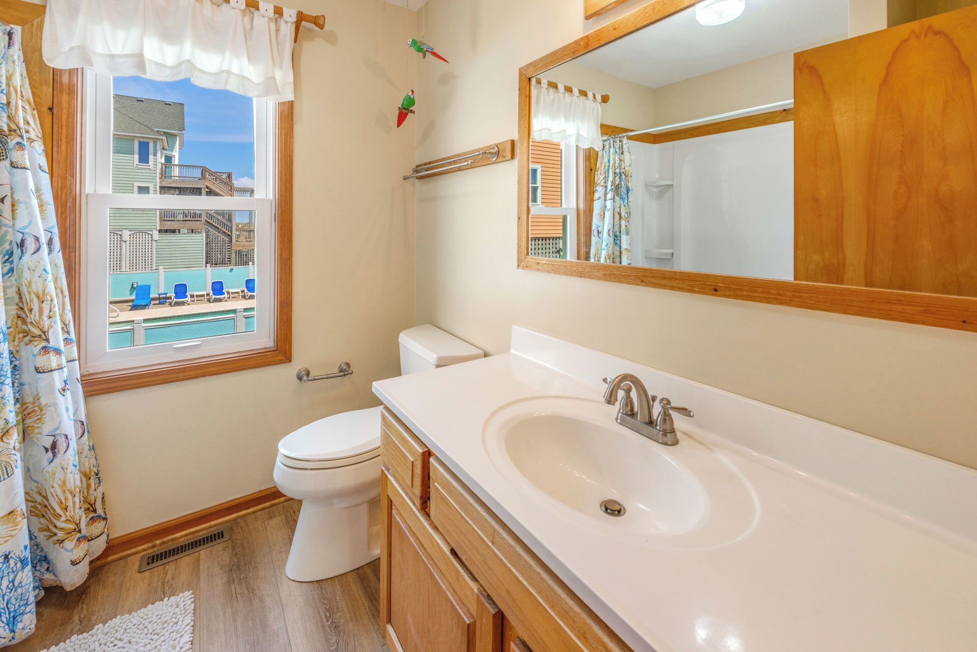 A bathroom with a large window, a toilet, a sink, and a mirror.