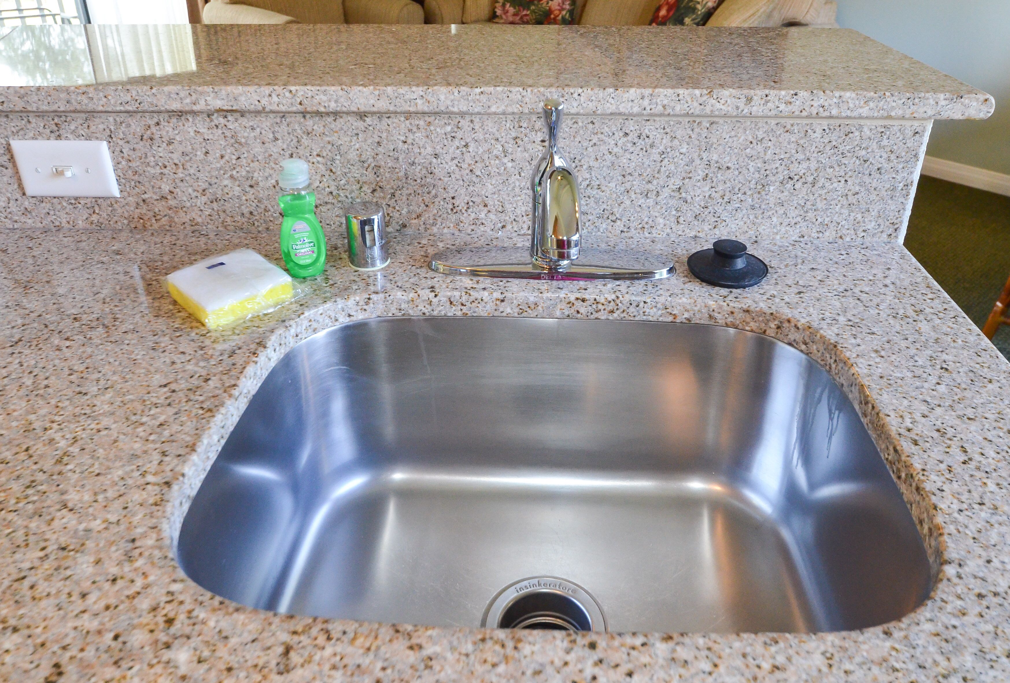 Eine Küche mit Spüle aus Edelstahl, einer Arbeitsplatte aus Granit und einem Wasserhahn.