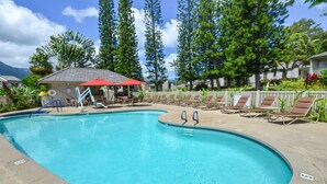 Une piscine avec des chaises longues et un petit bâtiment doté d’un toit rouge.
