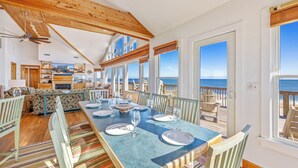 Een eethoek met een lange tafel voor zes personen, met uitzicht op een strand.