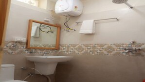 Un baño con inodoro, lavamanos, espejo, toallero y ducha.