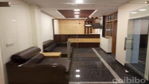 Una zona de recepción moderna con un mostrador de madera, asientos de cuero y una partición de vidrio.