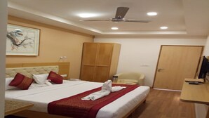 Una habitación de hotel con cama, armario de madera, escritorio y ventilador de techo.