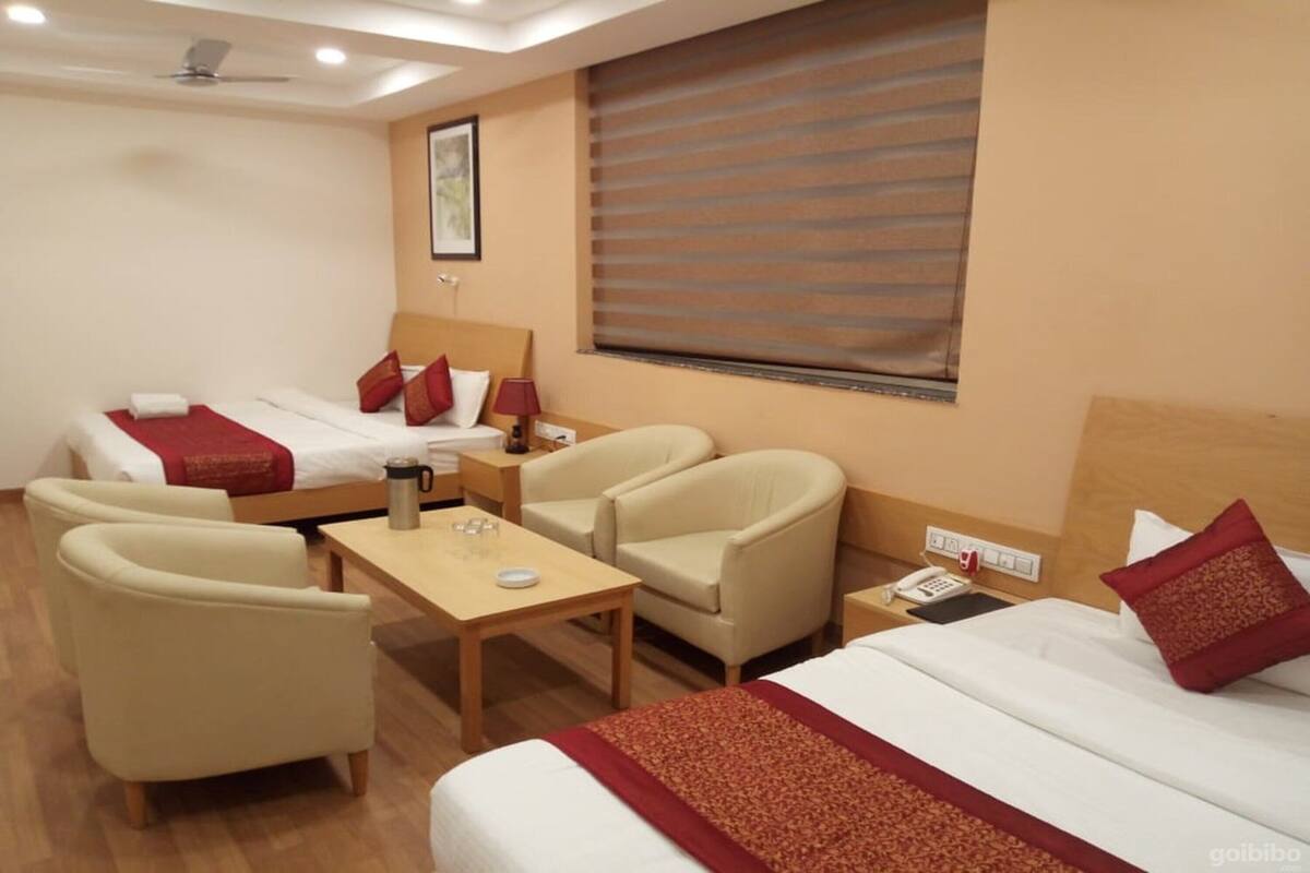 A hotel room with two beds, a sofa, a table, and a chair.