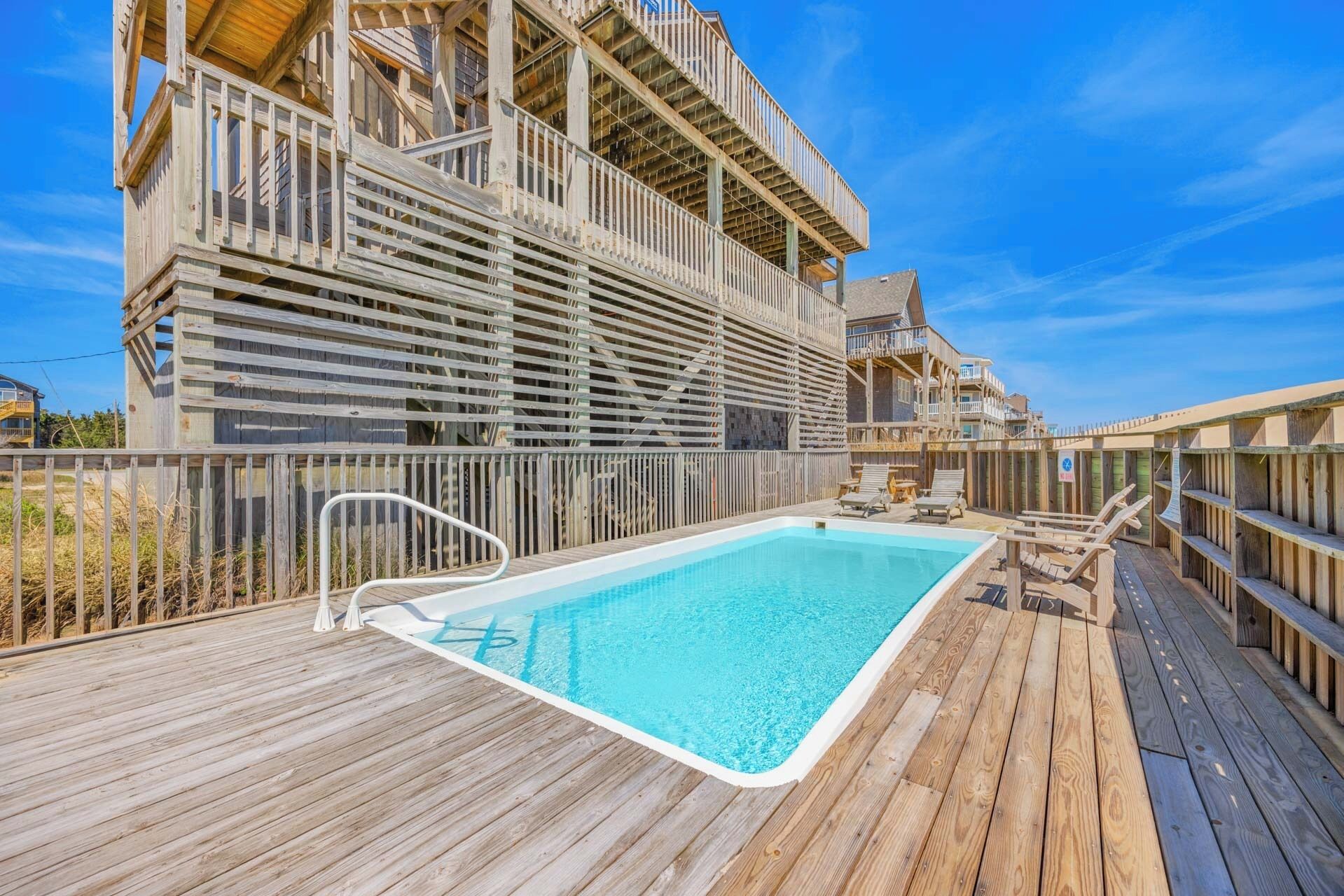 Beachside property featuring a private pool and multi-level deck under bright coastal skies—an exclusive retreat combining relaxation, comfort, and seaside charm.