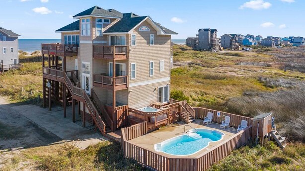 A multi-story beachfront property with a pool and outdoor seating. - Semi-Oceanfront Dog Friendly w/ Private Pool, Hot Tub, Game and Media Rooms (Rodanthe)