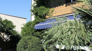 A multi-story building with balconies, potted plants, and a clear blue sky.