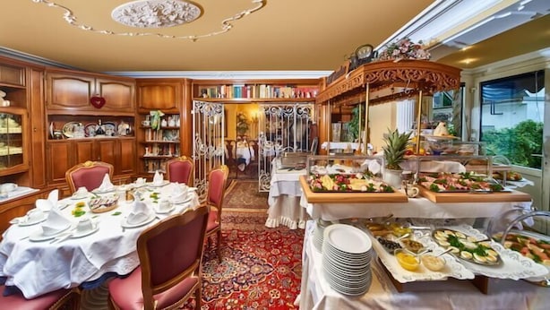 A dining area with a buffet setup, a library, and a chandelier.