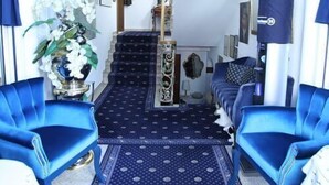 A hotel room with a blue carpet, a sofa, and a chair.