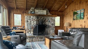 Una sala de estar acogedora con chimenea de piedra, sofás de cuero y un letrero que dice 'Welcome to the Lake'.