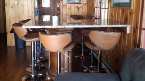 Un interior de madera con una zona de bar que incluye taburetes y un banco acolchado.