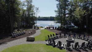 Un espace aménagé au bord du lac, avec des fauteuils Adirondack, un foyer et une vue sur le lac.