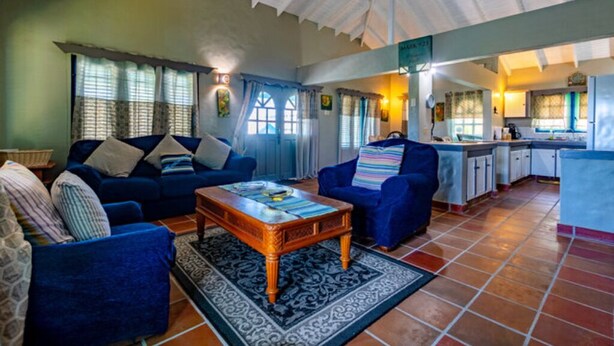 A cozy living room with a sofa set, a coffee table, and a patterned rug. - Lavaughn House - Restorations Tobago (Bon Accord)