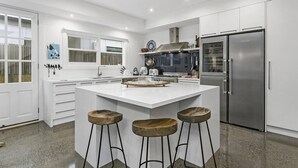 Una cocina moderna con una isla central, electrodomésticos de acero inoxidable y armarios blancos.