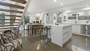 Una cocina moderna con una isla central, muebles blancos y electrodomésticos de acero inoxidable.