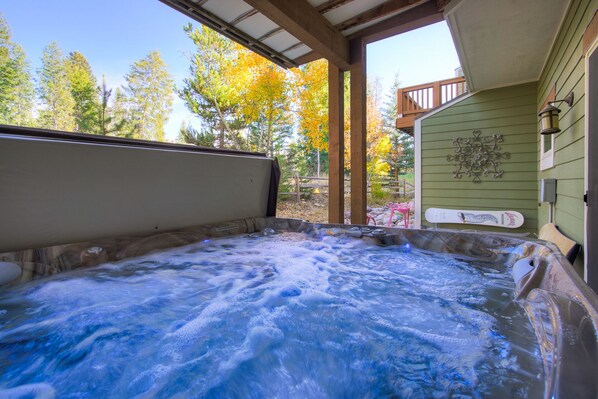 A hot tub with a wooden deck and a view of autumn trees. - Winter Park 4BR — Hot Tub, River Views & Downtown (Winter Park)