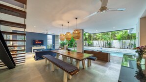 Ein modernes Wohnzimmer mit Pool, Holzmöbeln und einem Fernseher, der 'NETFLIX' anzeigt.