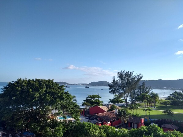 A coastal view with a swimming pool, red buildings, and boats on the water. - Penthouse with Fantastic Sea View, Pool and Barbecue on Large Terrace (Cachoeira do Bom Jesus)