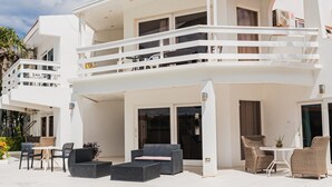 Ein modernes, zweistöckiges Gebäude mit Balkon, Sitzgelegenheit im Freien und einem großen Schiebeglastür.