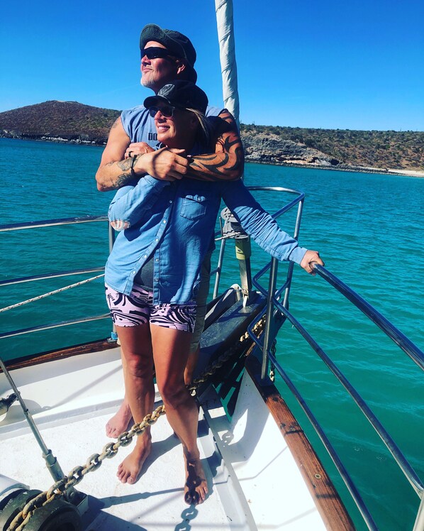 Dos personas en un bote, con una vista despejada del mar y tierra a lo lejos.