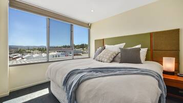 Relax in a stylish room with a large bed, green headboard, and city views.