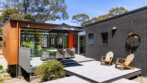 Un espace extérieur moderne, aménagé avec une structure en verre, une terrasse en bois et un bâtiment en briques.
