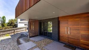 Un bâtiment moderne doté d’une façade en bois, de grandes portes coulissantes et d’un chemin en pierre menant à l’entrée.
