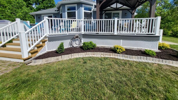 Une maison à deux étages dotée d’une terrasse couverte et d’un belvédère.