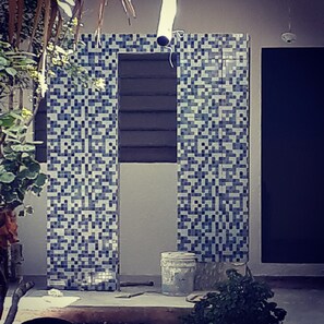 A room with a tiled wall featuring a geometric pattern, a window with horizontal blinds, and a small table with a jar and a plant. - 3.5 BLOCKS FROM OCEANFRONT WALK EVERYWHERE!!! (COZUMEL)