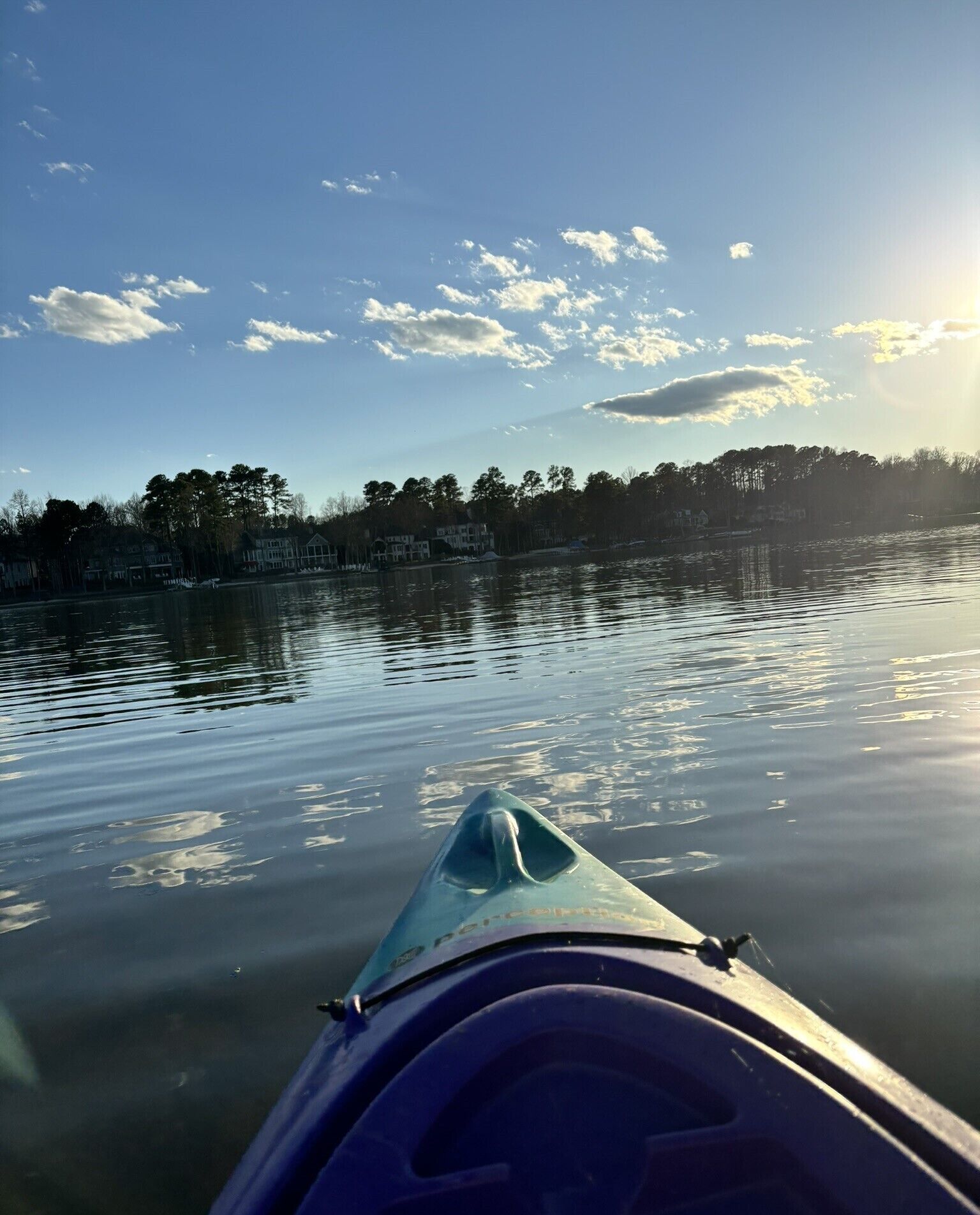 Un kayak sur une eau calme, sous un ciel dégagé, avec des arbres en arrière-plan.