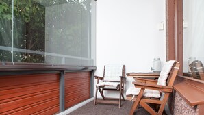 A balcony with a red shutter, two wooden chairs, a small table, and a view of trees through a glass door. - Feel yourself at  Three Bears appartment :) (Kotka)