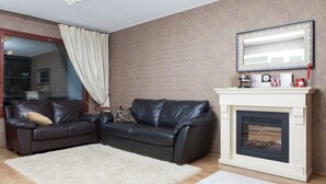 A living room with a fireplace, two leather sofas, a white rug, and a large mirror above the fireplace. - Feel yourself at  Three Bears appartment :) (Kotka)