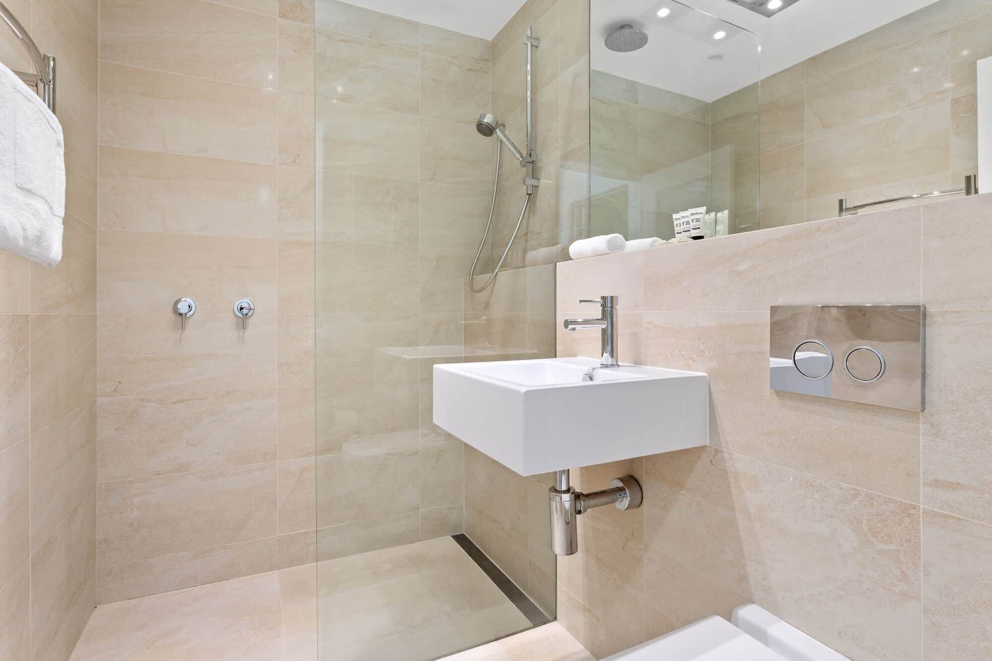 Une salle de bain moderne avec une douche à parois de verre, un lavabo blanc et des toilettes.