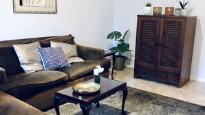 Ein Wohnzimmer mit braunem Sofa, einem Couchtisch, einem Schrank und einem gerahmten Kunstwerk an der Wand.