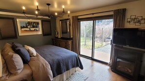 A bedroom with a large bed, a TV, a fireplace, and a sliding glass door to a deck. - Luxery Waterfront Oasis  4bd 5minutes from the Jackson Town Square & Whole Foods (Jackson)