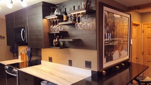 A modern kitchen with dark cabinetry, a marble countertop, and a wine rack with bottles and glasses. - Luxery Waterfront Oasis  4bd 5minutes from the Jackson Town Square & Whole Foods (Jackson)