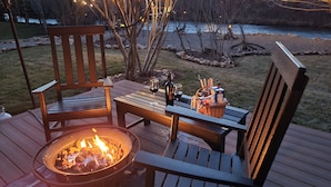 A wooden deck with two chairs, a table, a fire pit, and a basket with items. - Luxery Waterfront Oasis  4bd 5minutes from the Jackson Town Square & Whole Foods (Jackson)