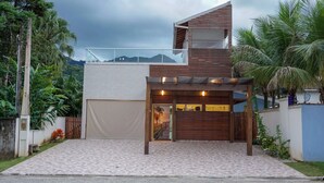 Uma casa moderna com entrada coberta, varanda e vista para o verde ao redor.