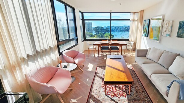 Una sala de estar moderna con un ventanal grande, un sofá, una mesa de centro y un comedor.