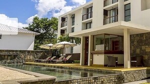Un hotel moderno con zona de piscina, asientos exteriores y fachada de piedra.