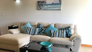 Una sala de estar con un sofá color beige, dos almohadas a rayas, un tazón color turquesa y una mesa de centro negra.