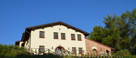 A two-story building with a flat roof, multiple windows, and a small porch area.
